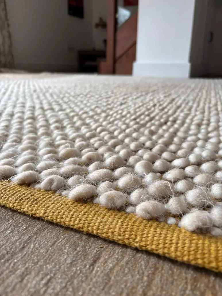 Close-up of a wool loop rug and its repaired edge
